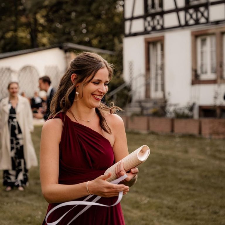 Freie Traurednerin Katharina Dabrock im festlichen roten Kleid vor einem historischen Gebäude.