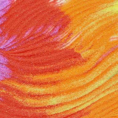 Bunte, geschwungene Muster in kräftigen Rot- und Orangetönen aus Sand.