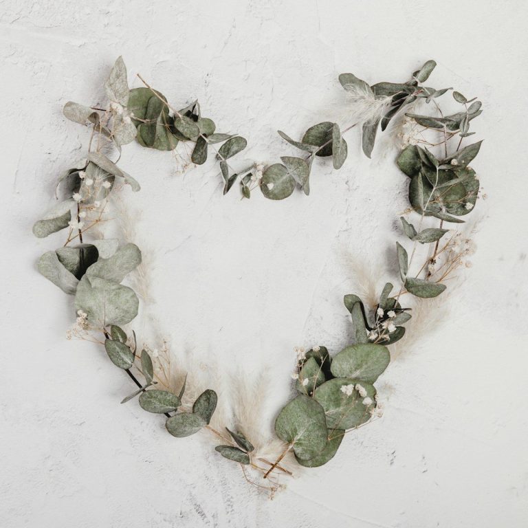 Herzförmiger Kranz aus Eukalyptus und Trockenblumen an einer Wand.