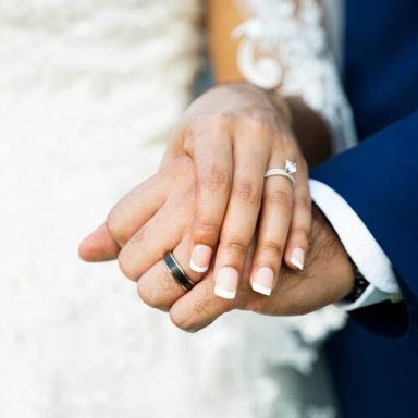 Hochzeitsringe werden von einem Brautpaar gehalten, Hände in eleganter Pose.